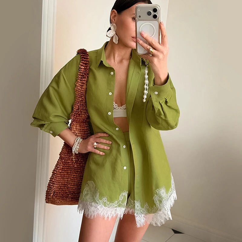 Woman taking a mirror selfie wearing a green dress with lace trim, holding a brown woven bag.