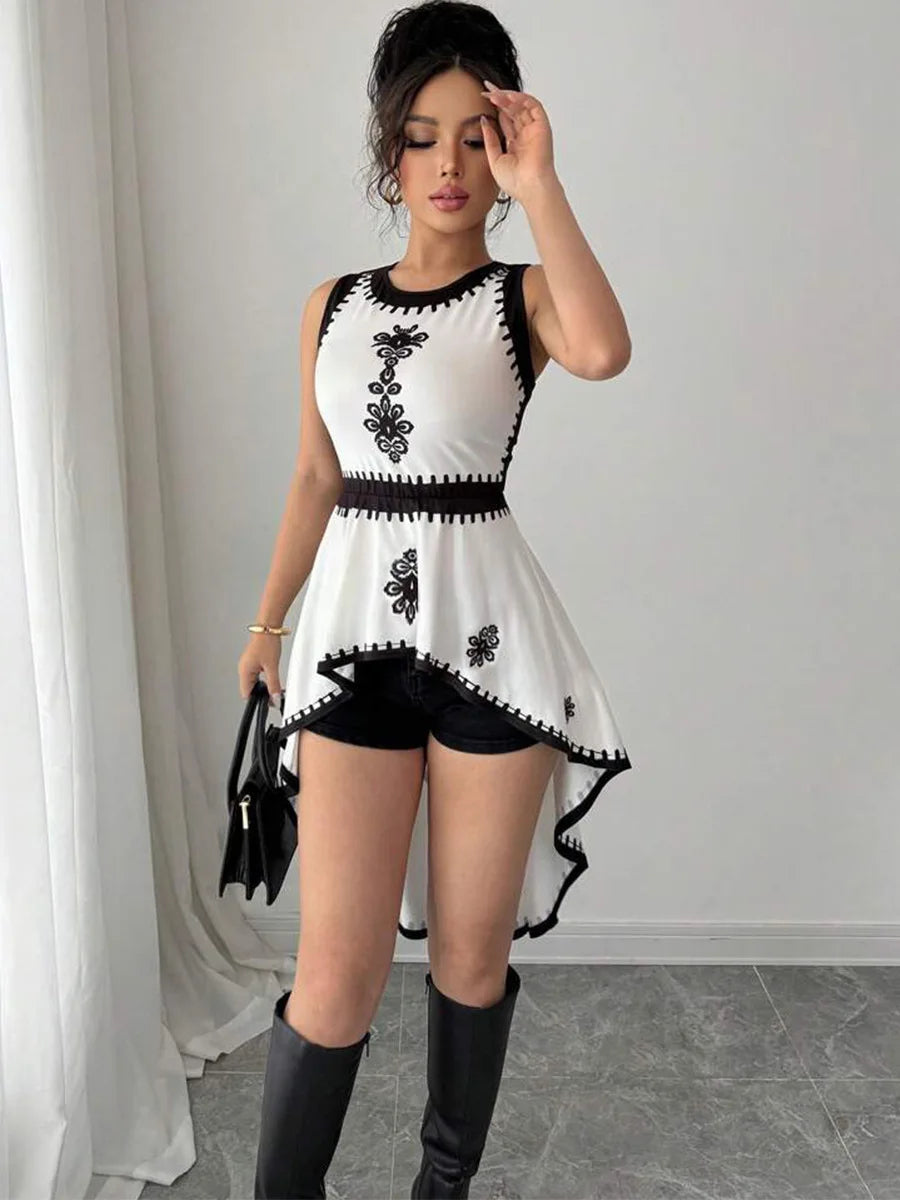 Woman wearing a black and white dress with floral patterns in a minimalistic setting.