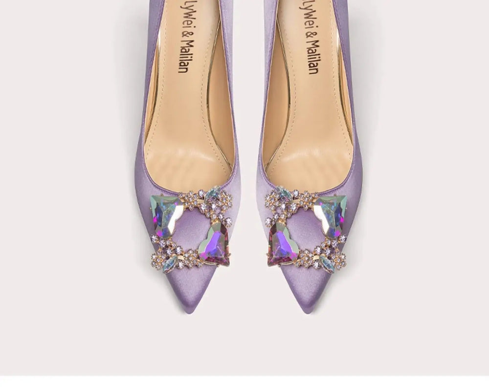 Pair of purple high-heeled shoes with embellishments on a white background