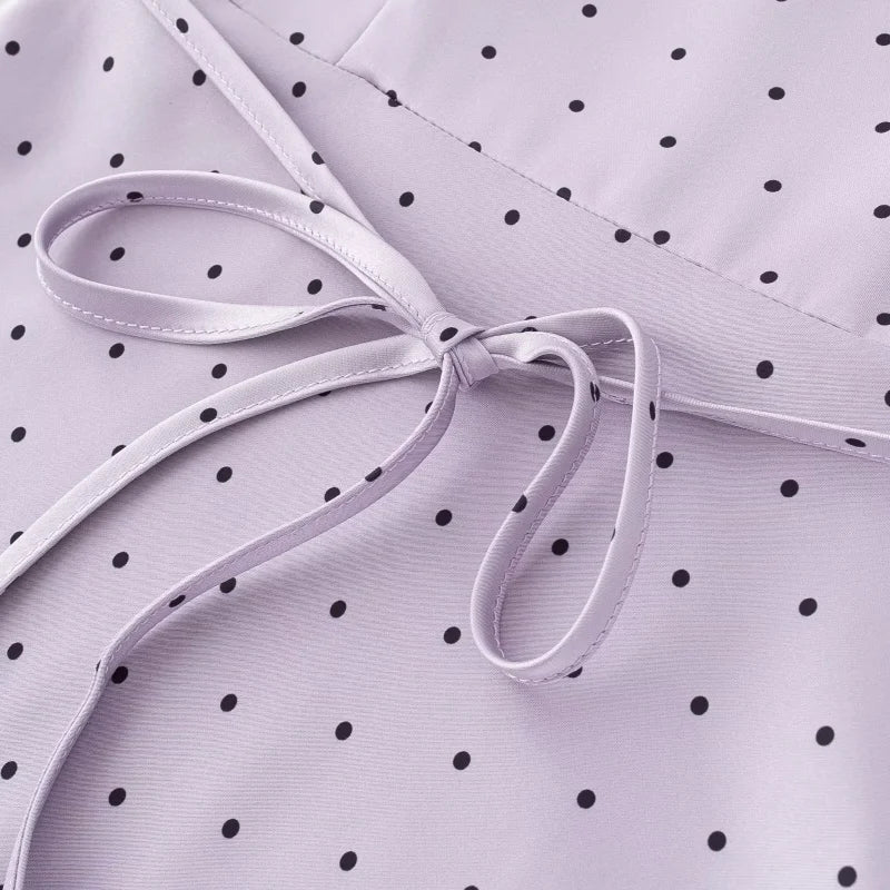 Close-up of a white ribbon on a purple fabric with black polka dots