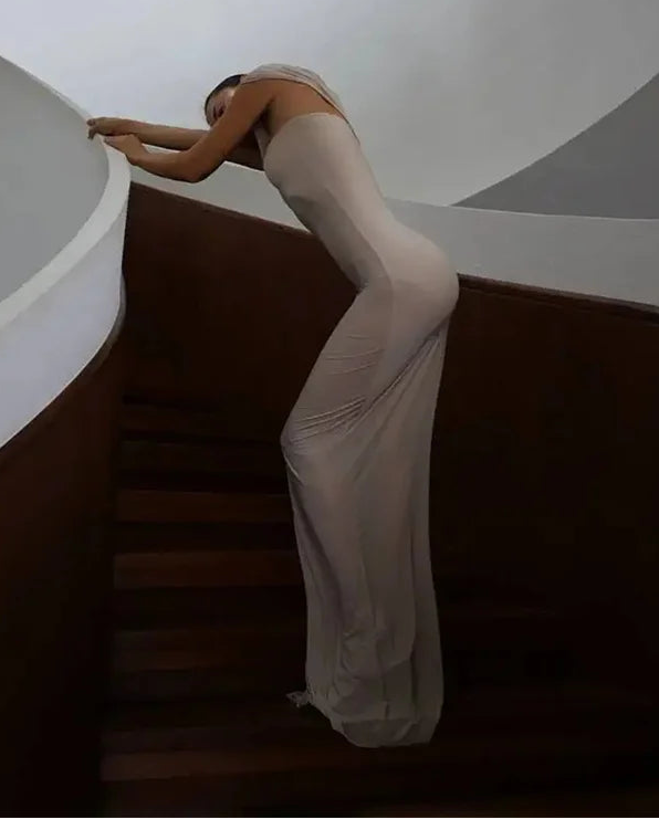 Person in a white dress standing on a staircase with a minimalistic background
