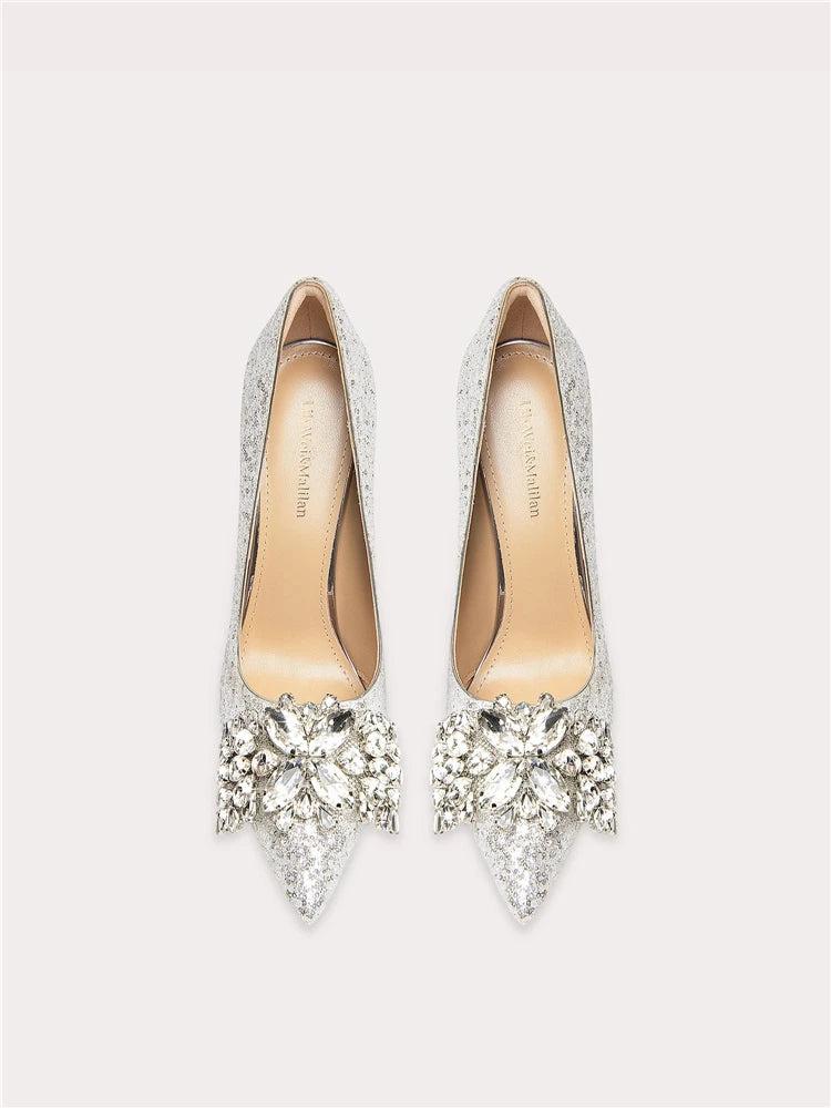 Pair of high-heeled shoes with crystal embellishments on a light gray background