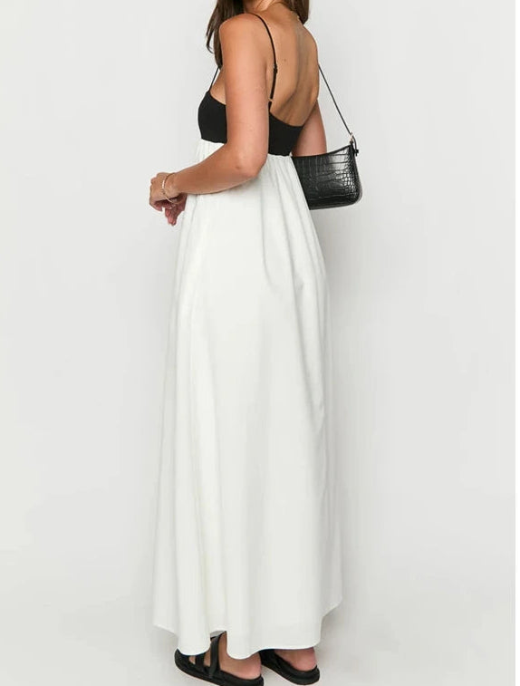 Woman wearing a black top and white skirt with a black handbag on a white background