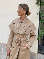 A stylish woman wearing a double-breasted trench coat with a shawl collar and belt, showcasing its elegant design.