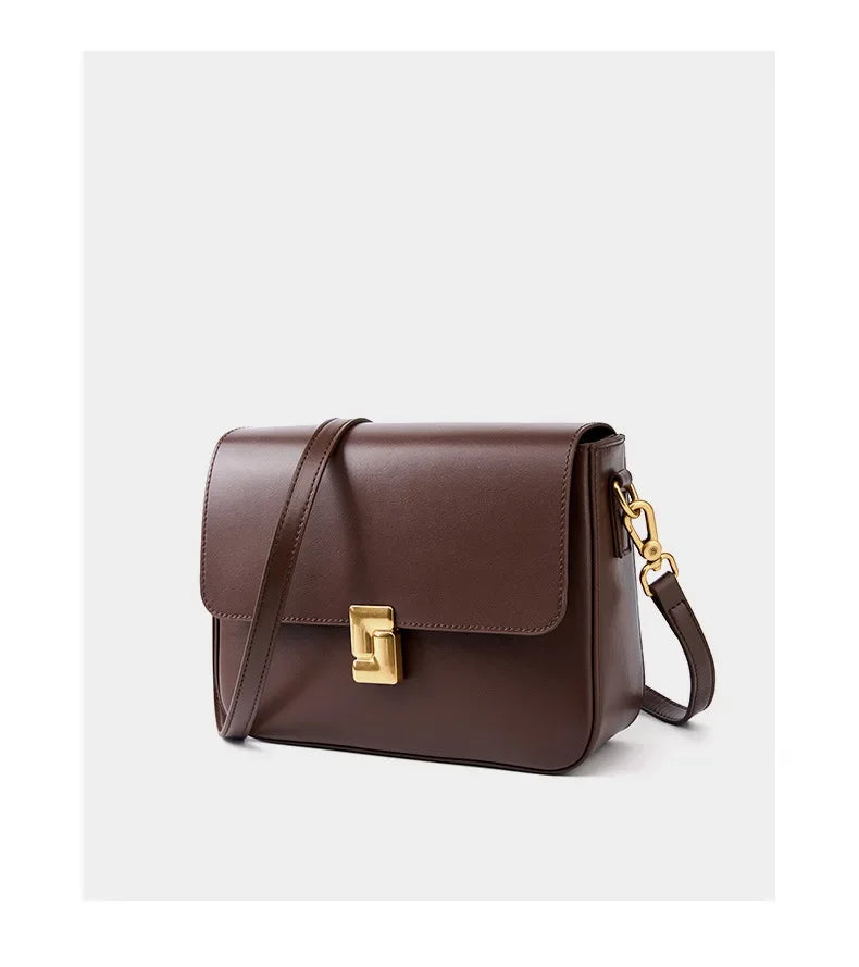 Brown leather handbag with a gold clasp on a light gray background