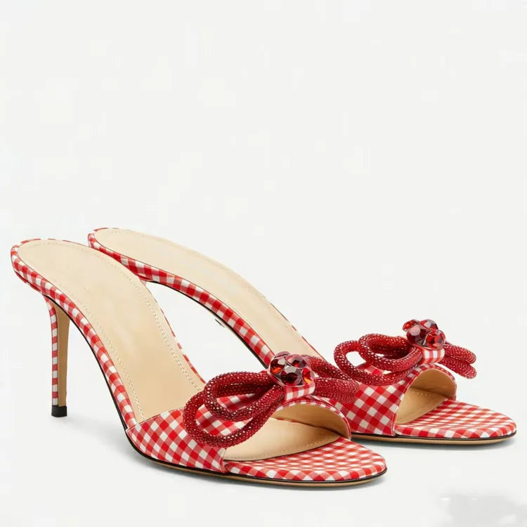 Red and white checkered high-heeled sandals with decorative straps on a white background