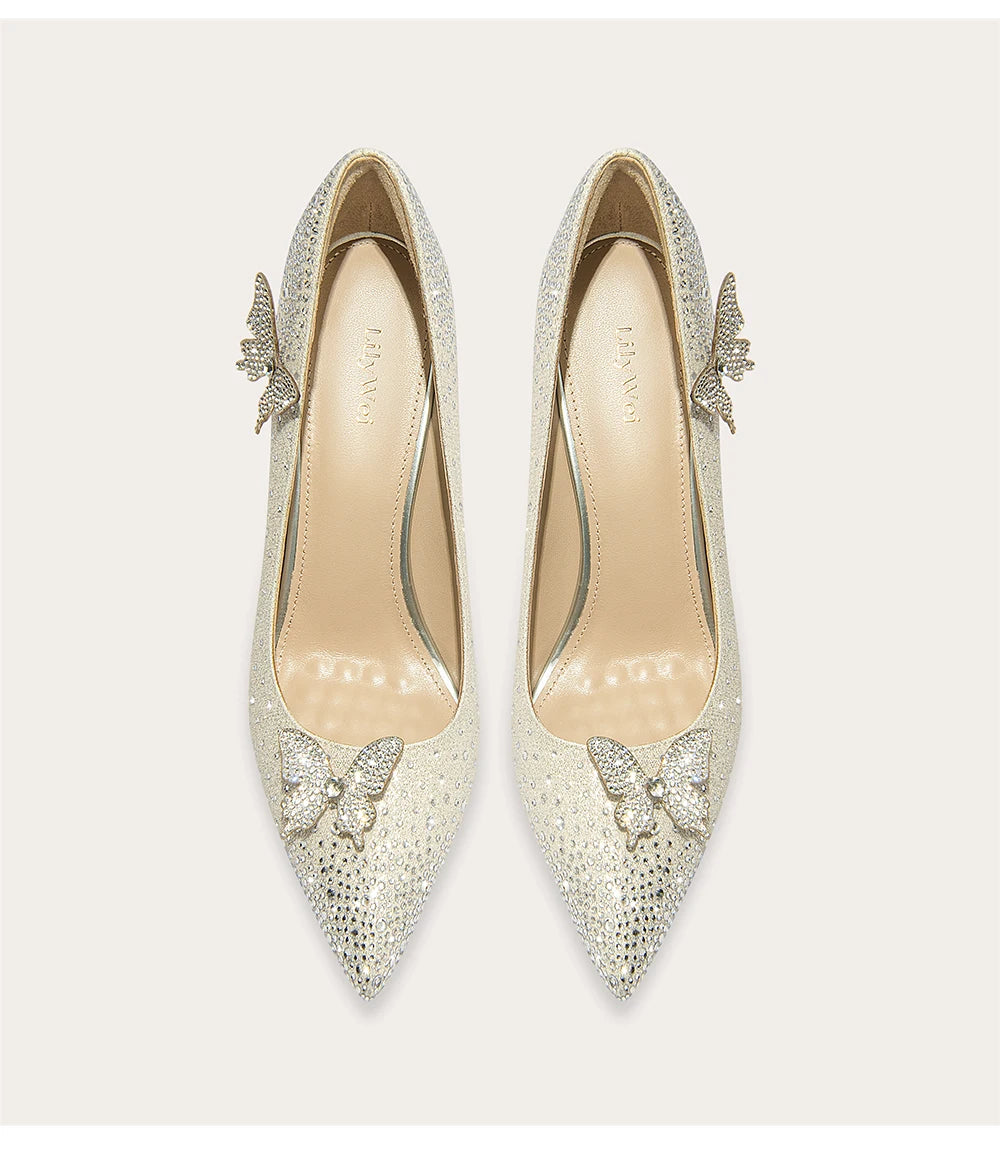Pair of silver high-heeled shoes with butterfly embellishments on a light background