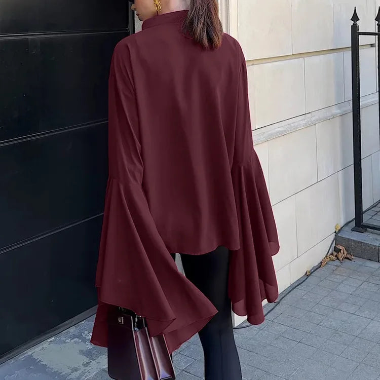 Person wearing a burgundy long-sleeve top standing on a sidewalk.