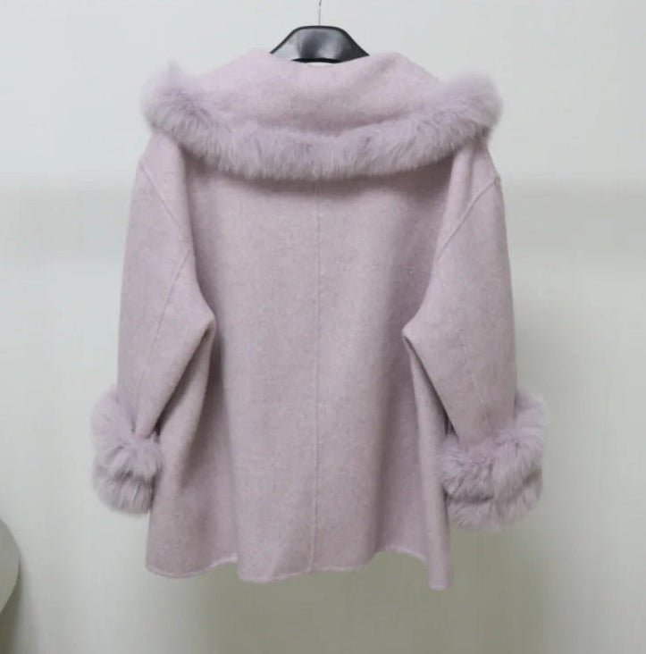 Pink coat with fur trim on a hanger against a white background
