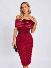 Woman wearing a burgundy off-shoulder dress with floral details on a white background