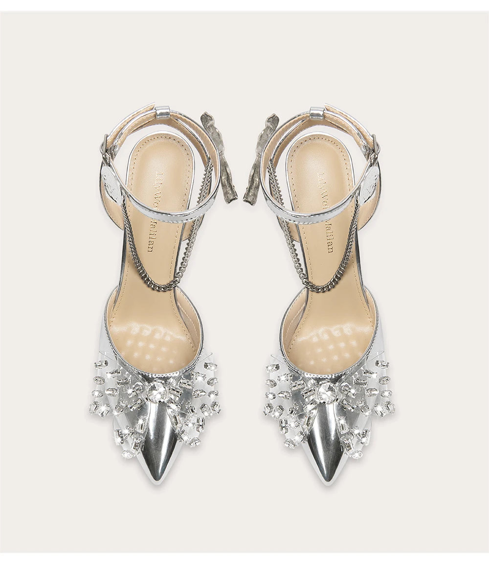 Silver high-heeled shoes with crystal embellishments on a white background