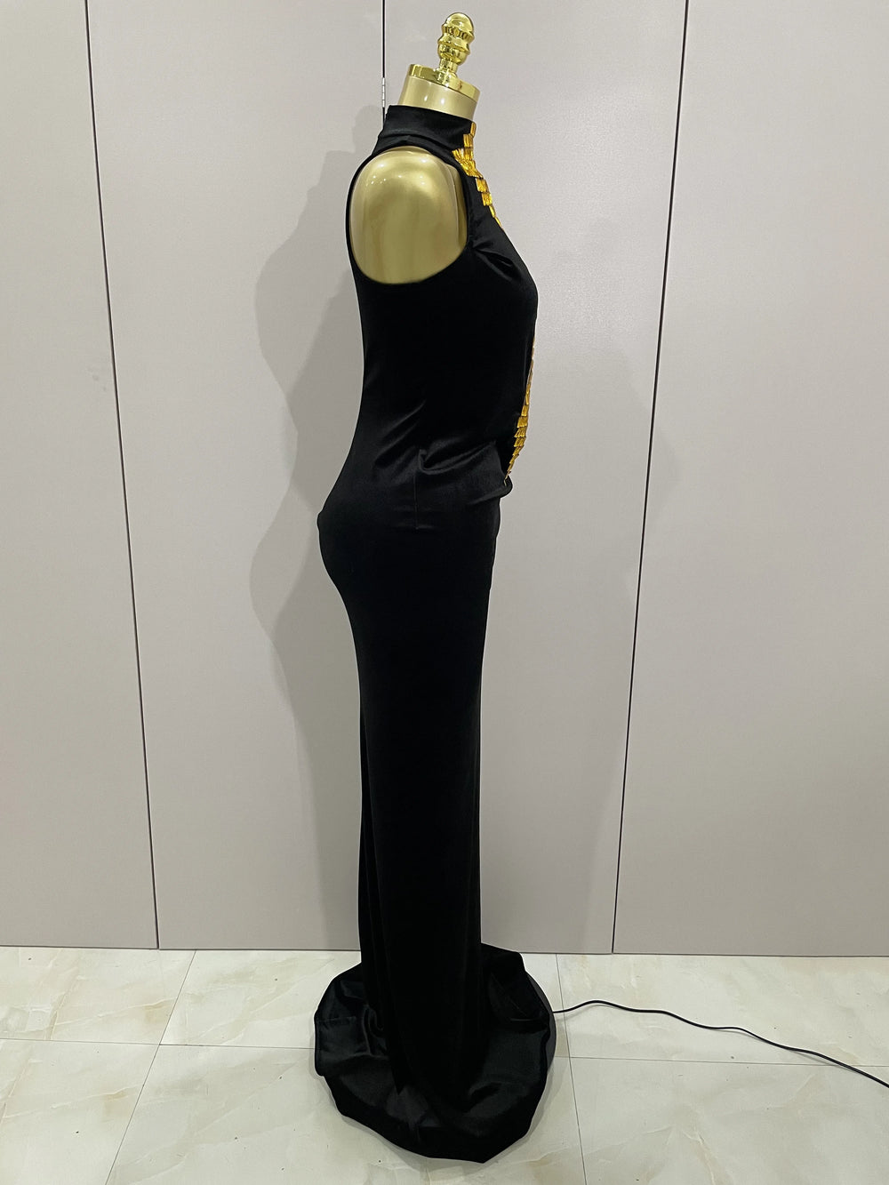 Black evening gown on a mannequin against a light gray wall.