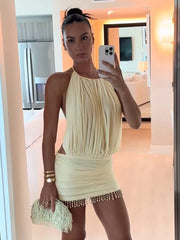 Woman taking a mirror selfie wearing a light-colored dress with fringe details.