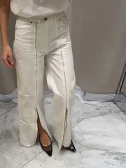 Person wearing light-colored jeans with a high slit on a marble floor.