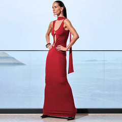 Woman in a red evening gown standing against a light blue wall.