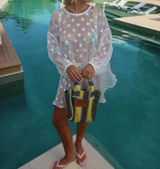 Person holding a colorful bag by a pool