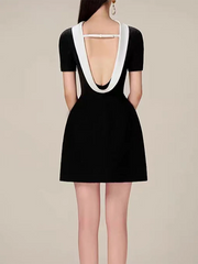 Black dress with white trim on a plain background