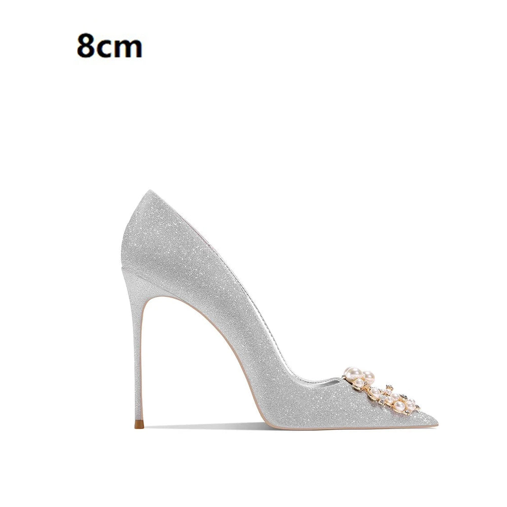 Silver high-heeled shoe with decorative elements on a white background