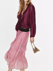 Model wearing a pink ruffled maxi skirt with a dark top.