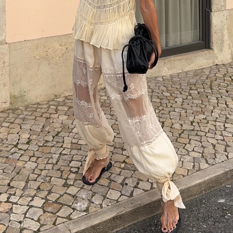 Person wearing a white lace outfit with black sandals on a cobblestone street.