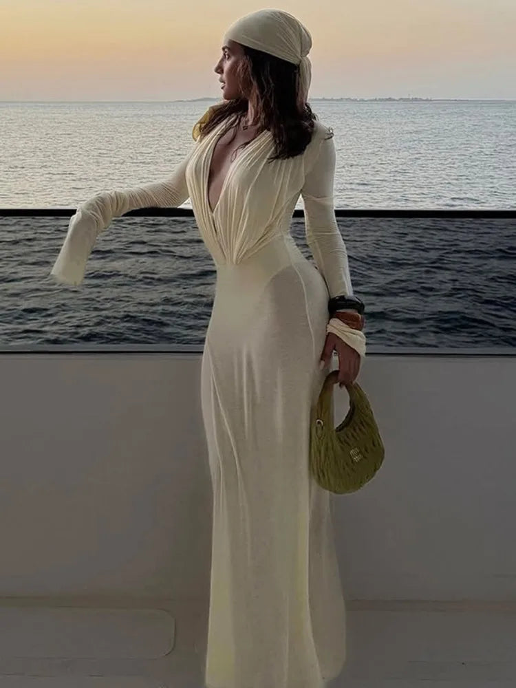 Woman in a white dress standing by the ocean at sunset