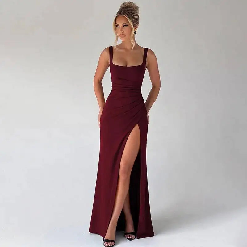 Woman wearing a burgundy evening gown with a high slit on a plain background