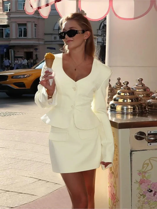 Woman in a light-colored suit holding an ice cream cone on a city street.