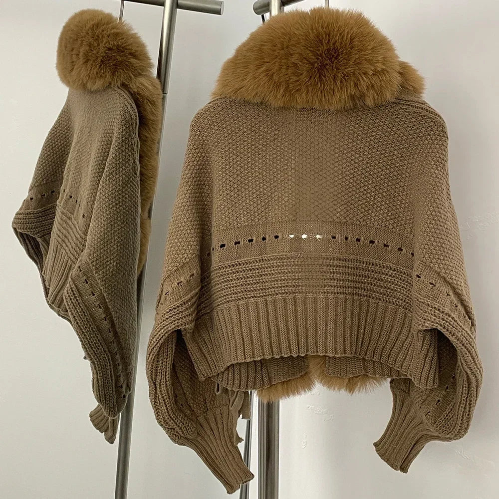 Brown knitted poncho with fur collar on a stand against a white background
