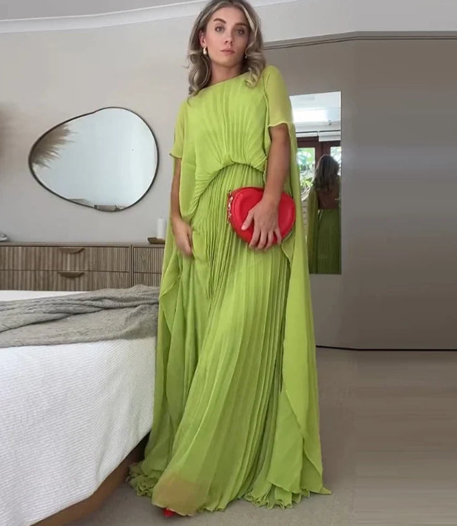 Woman in a green dress holding a red clutch in a bedroom setting