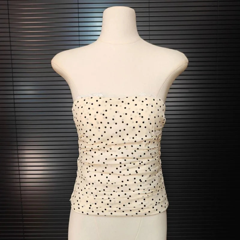 Beige strapless top with black polka dots on a mannequin against a dark background