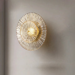 A sleek postmodern glass wall sconce illuminating a modern living room with soft, diffused light. B