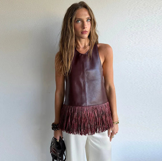 Woman wearing a brown leather halter top with fringe details against a plain background