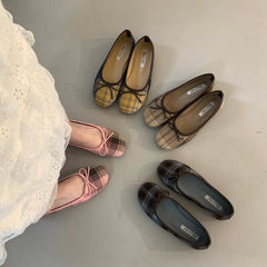 A person wearing pink checked ballet flats with a white lace dress