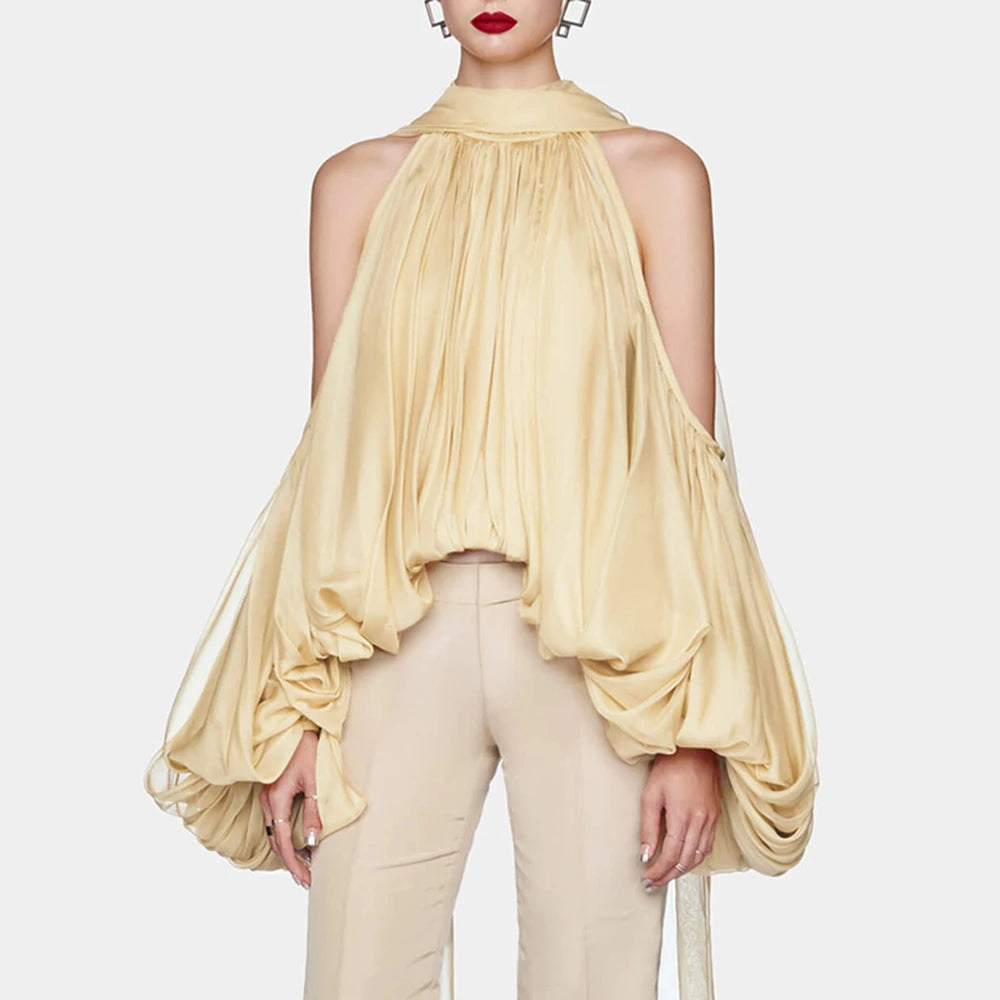 Woman wearing a flowing beige top and pants on a white background