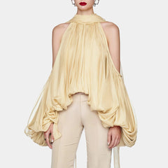 Woman wearing a flowing beige top and pants on a white background