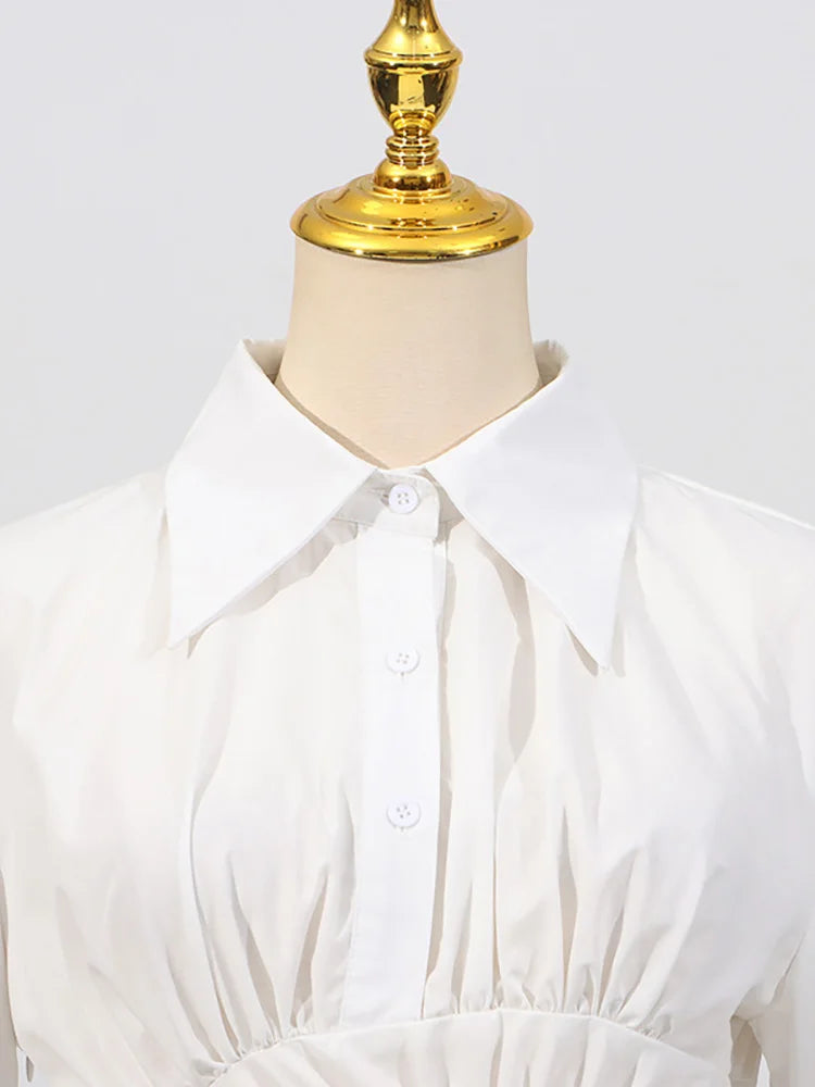 White blouse on a mannequin with a gold top against a white background