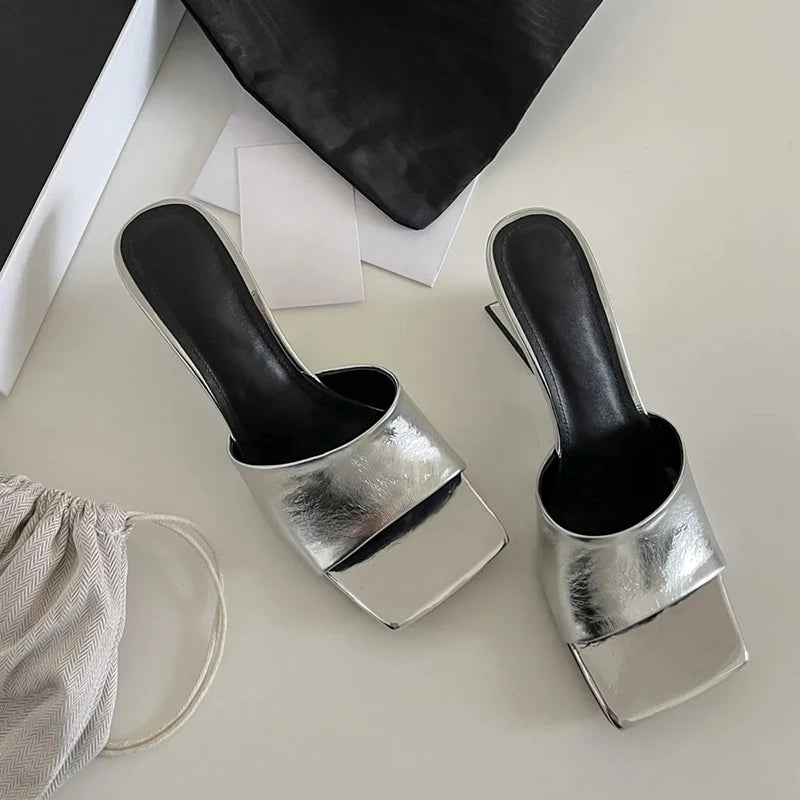 Two metallic shoe polish cups with black handles on a light surface.