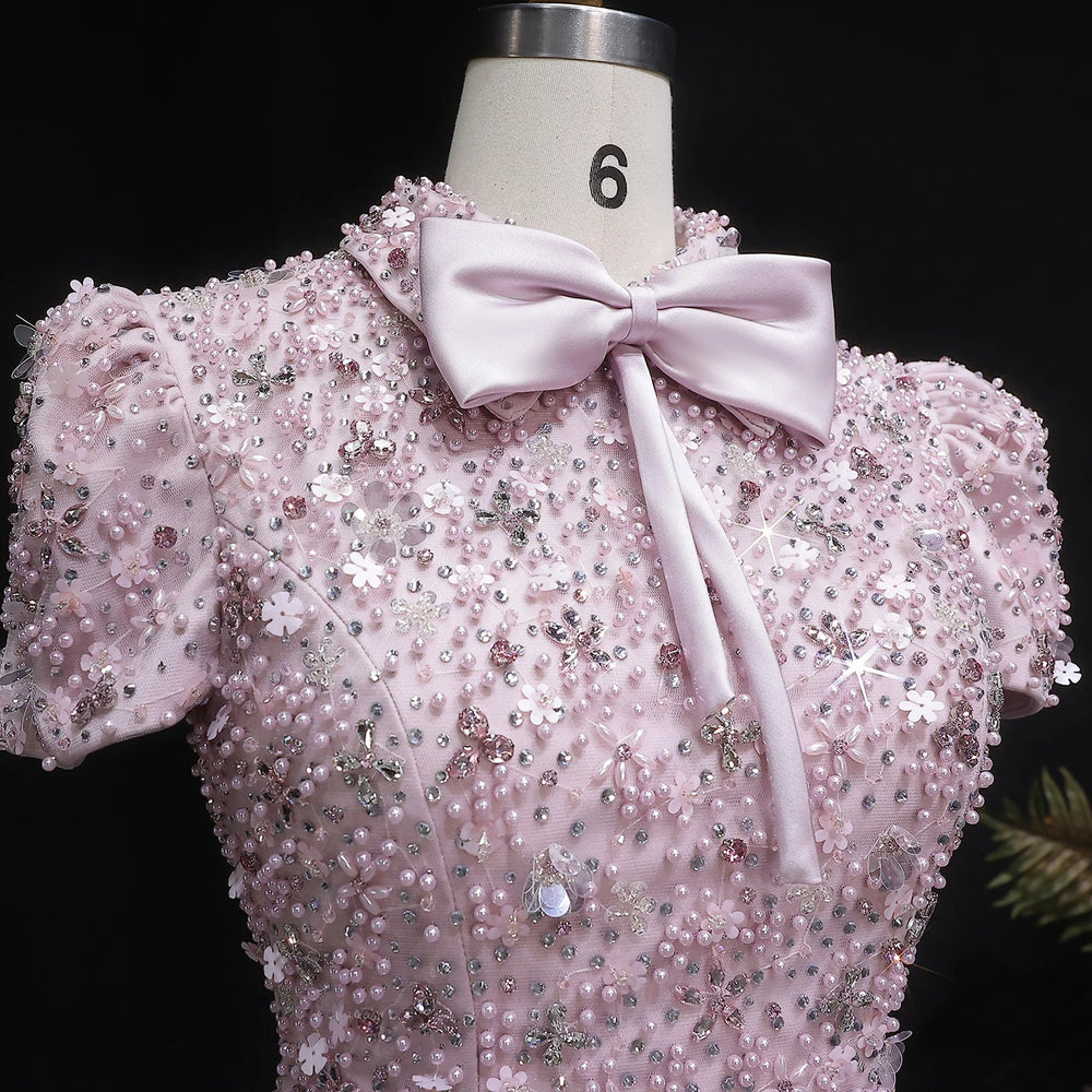 Pink beaded top with a bow on a mannequin against a black background