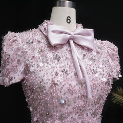 Pink beaded top with a bow on a mannequin against a black background