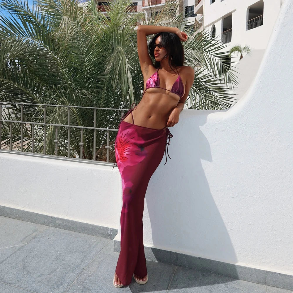 Woman in a pink bikini and magenta pants standing on a balcony with palm trees in the background
