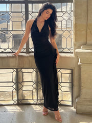 Model leaning on a window frame wearing a black ruffled halter neck maxi dress