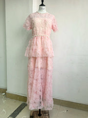Pink lace dress on a mannequin against a white wall.
