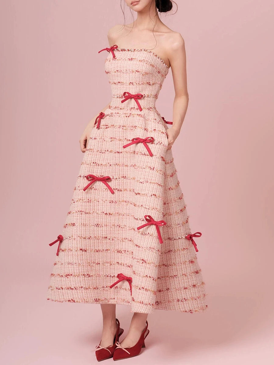 Woman wearing a strapless dress with red bows on a pink background