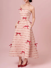 Woman wearing a strapless dress with red bows on a pink background