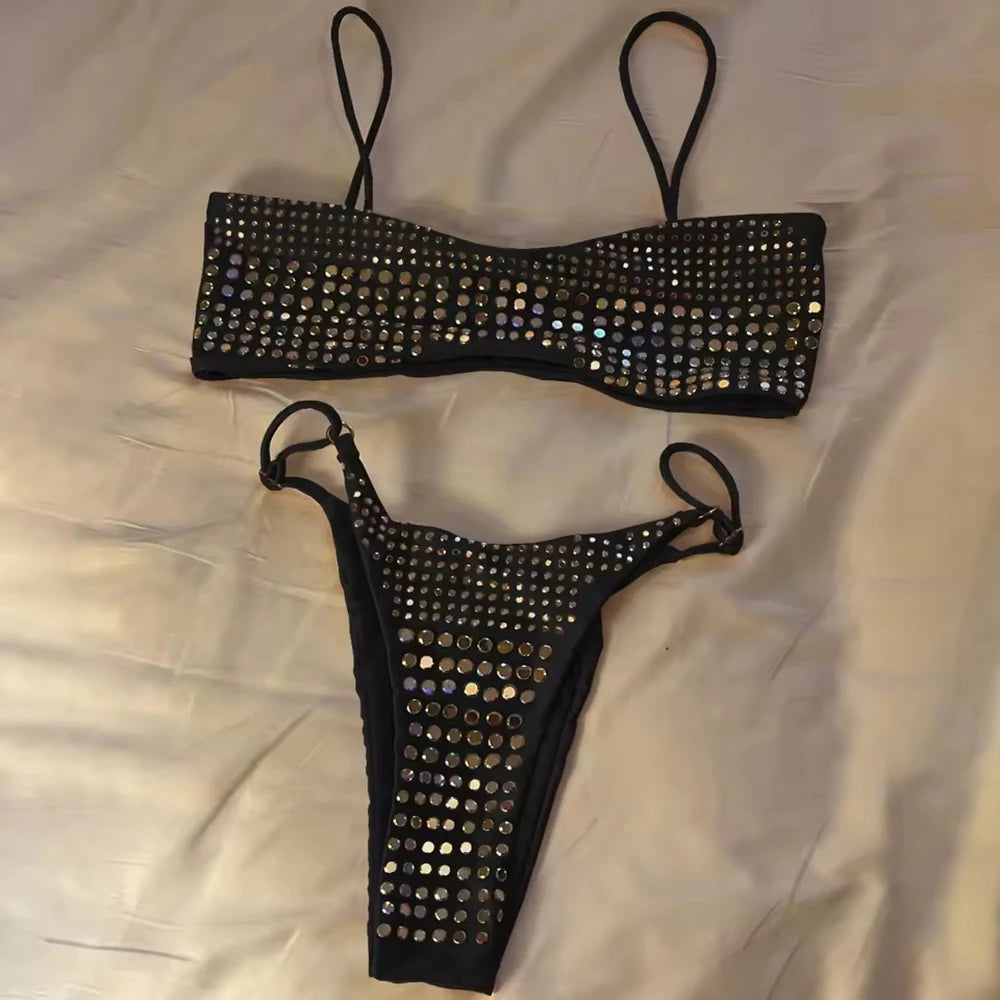 Black embellished bikini set laid flat on a white surface.