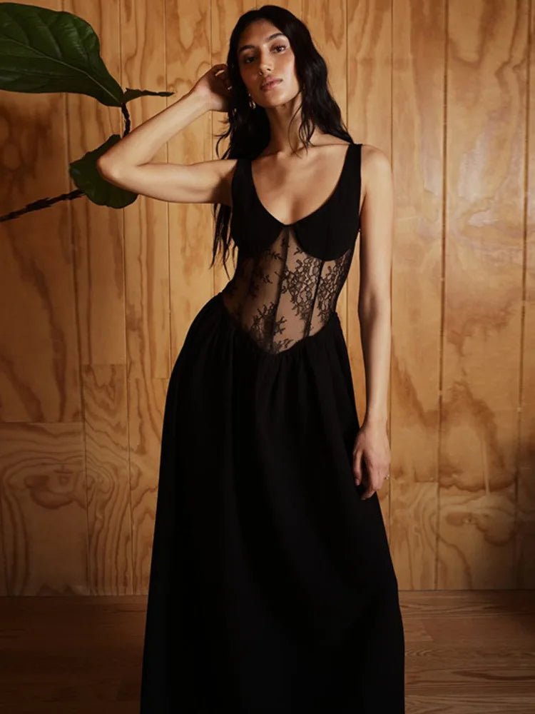 Woman wearing a black lace dress against a wooden wall.