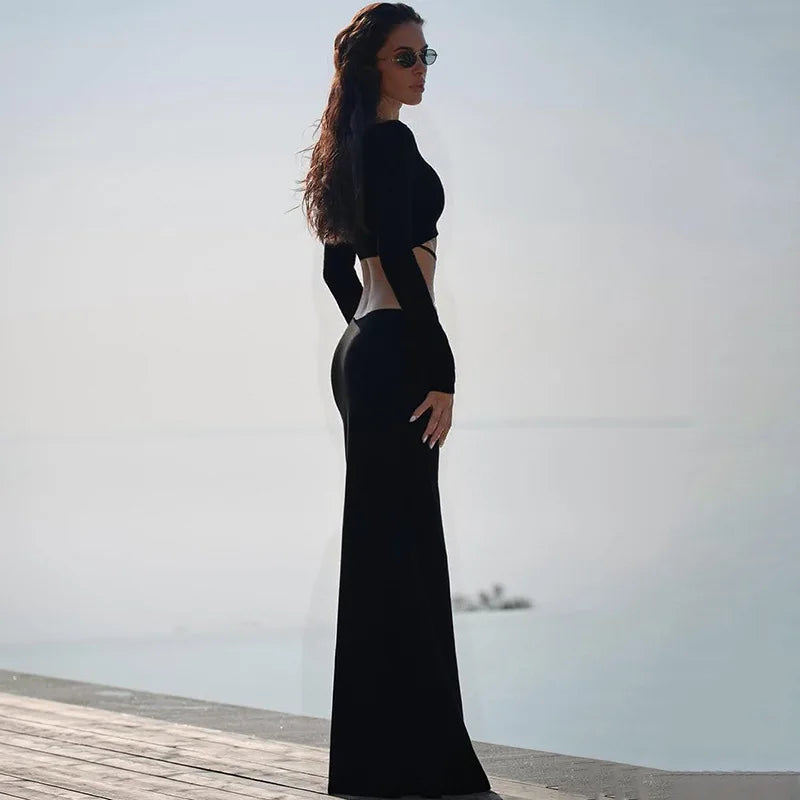 Woman in a black evening gown standing on a wooden pier with a clear sky background