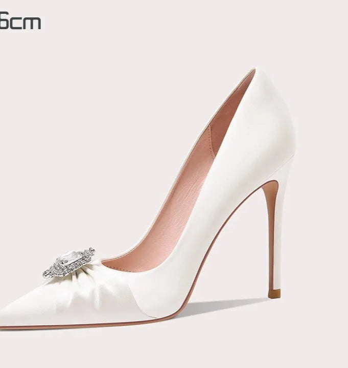 White high-heeled shoe with a decorative bow on a light gray background