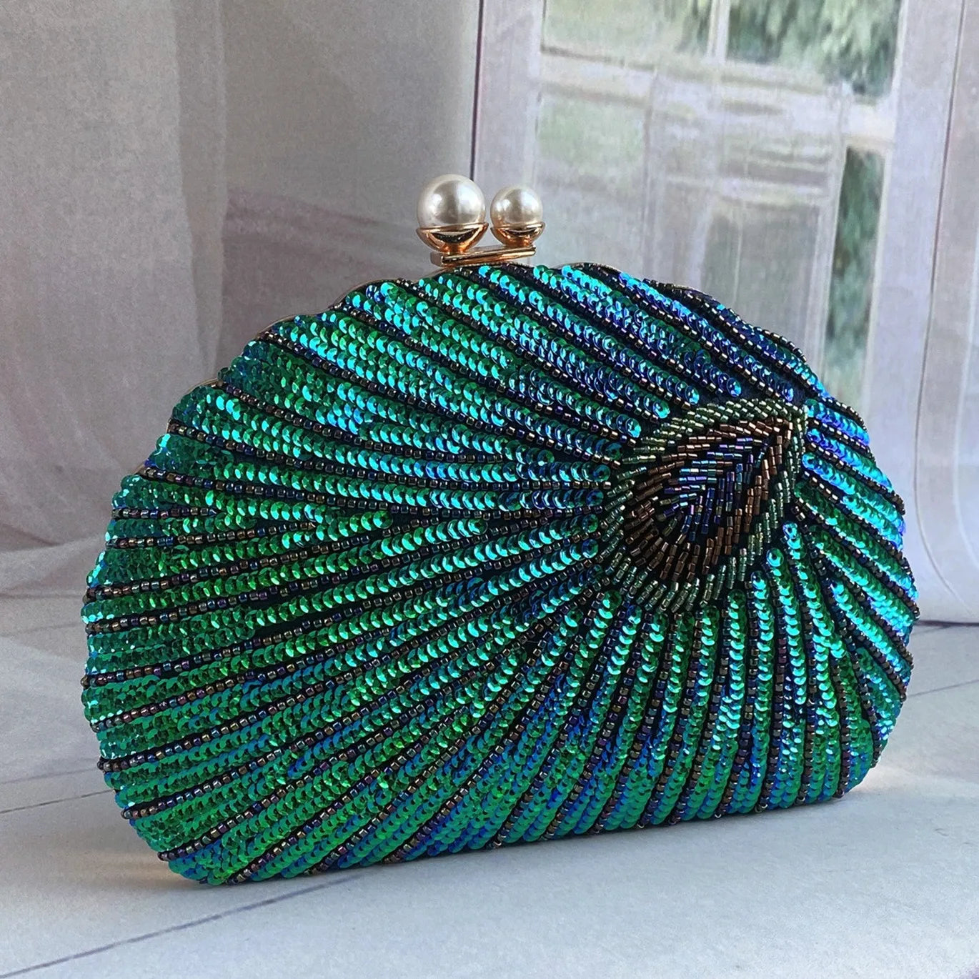 A close-up of a vintage-style clutch bag, showcasing intricate bead embroidery and a clasp closure