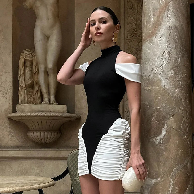 Woman in a black and white outfit posing in an elegant interior setting with classical sculpture.